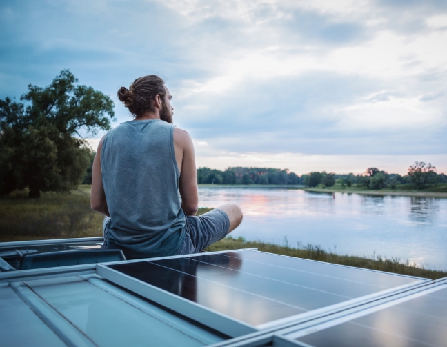 Homme sur un camping-car avec des panneaux solaires