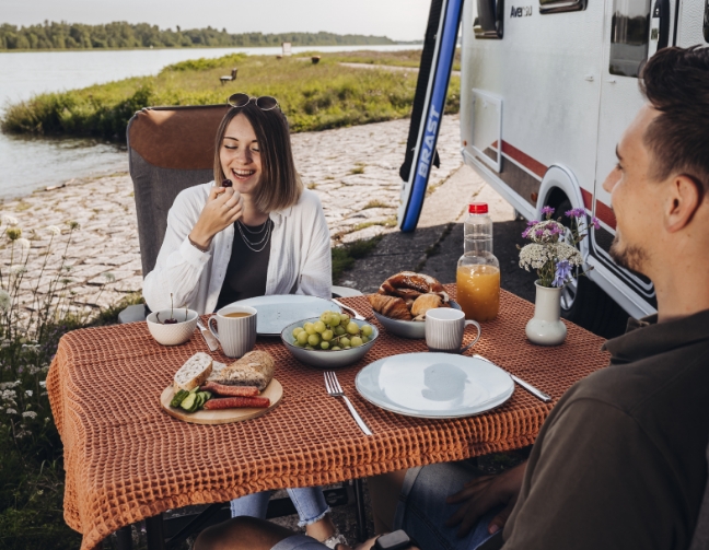 Couple devant un camping-car qui sont entrain de déjeuner