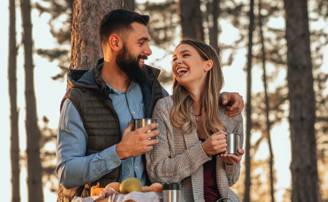 couple-heureux-boit-de-leau-en-foret-camping